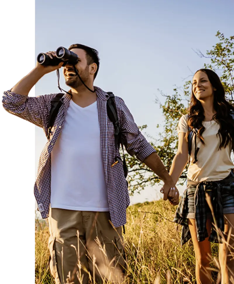 Pareja explorando el campo con binoculares disfrutando de un viaje personalizado con Concierge VIP